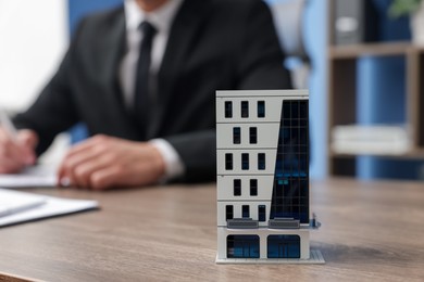 Photo of Real estate agent working at desk in office, focus on house model