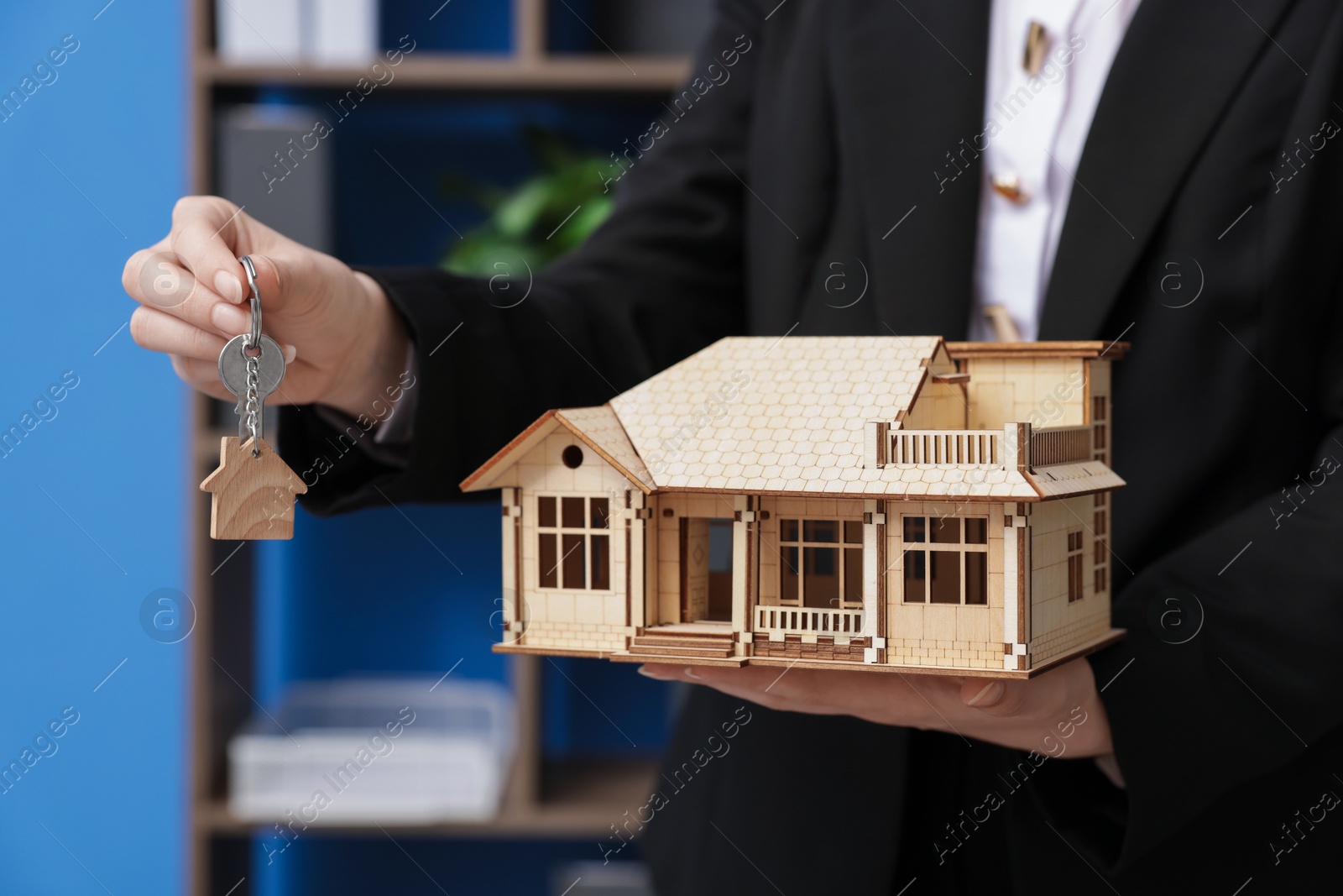 Real estate agent holding house model and key in office, closeup Photo of Real estate agent holding house model and key in office, closeup