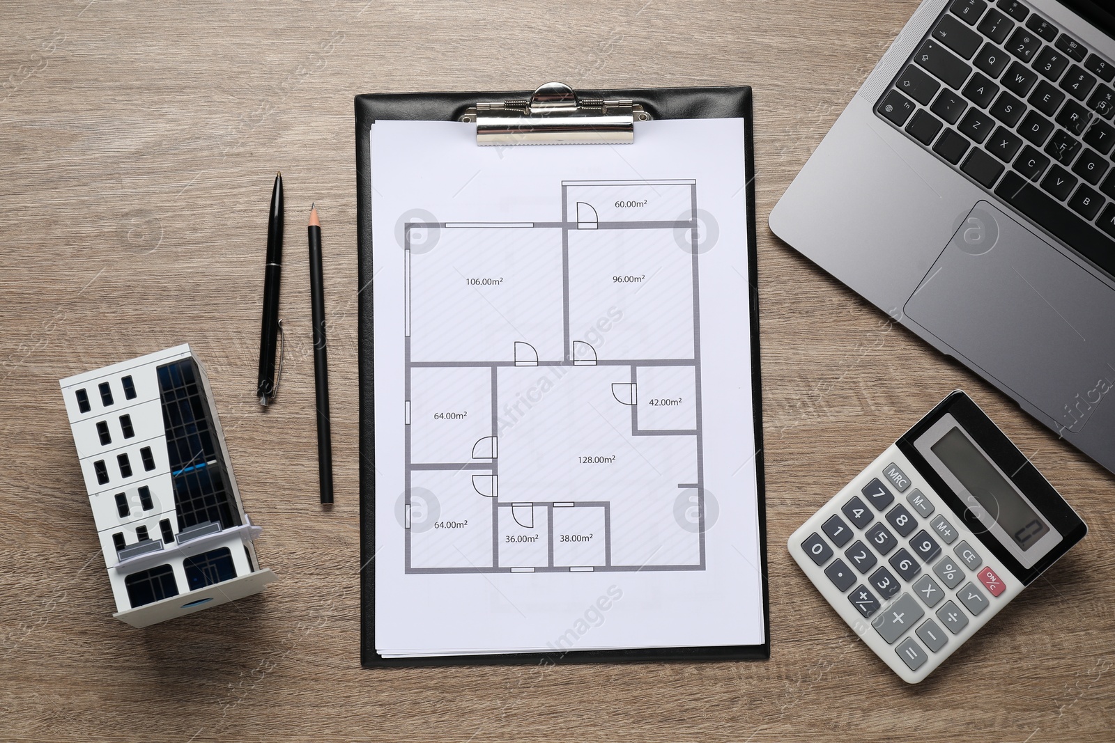 Real estate. Apartment building model, floor plan, calculator and laptop on wooden table, flat lay Photo of Real estate. Apartment building model, floor plan, calculator and laptop on wooden table, flat lay