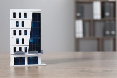 Photo of Real estate. Apartment building figure on wooden table indoors, space for text
