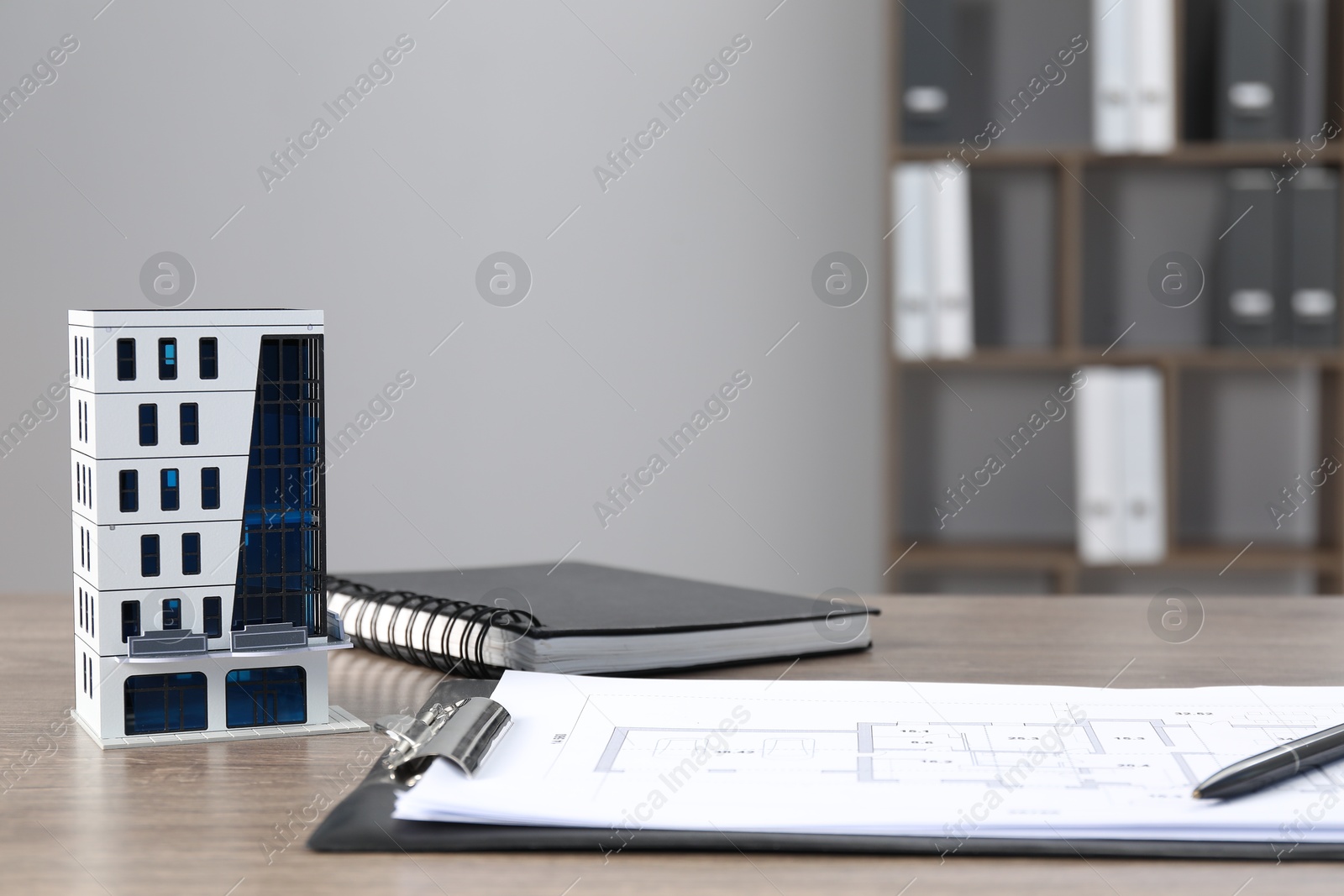 Photo of Real estate. Apartment building model, floor plan and notebook on wooden table indoors. Space for text
