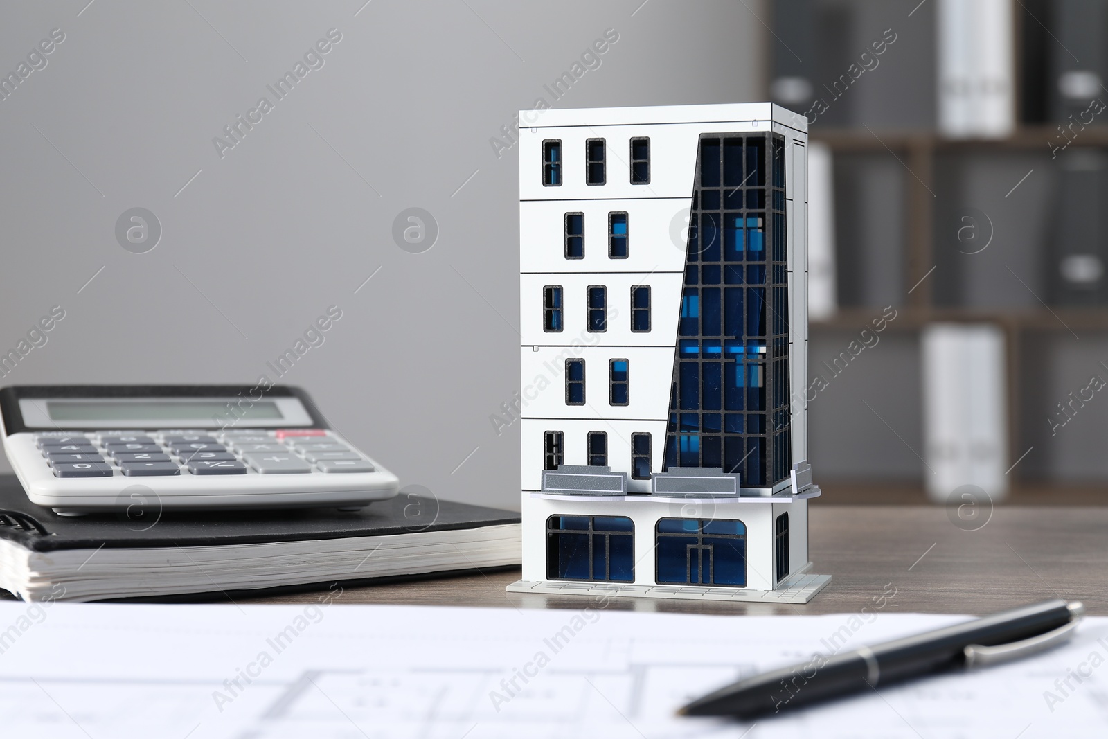 Real estate. Apartment building model, floor plan, calculator and notebook on wooden table indoors, closeup Photo of Real estate. Apartment building model, floor plan, calculator and notebook on wooden table indoors, closeup