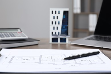 Photo of Real estate. Apartment building model, floor plan and laptop on table indoors, selective focus