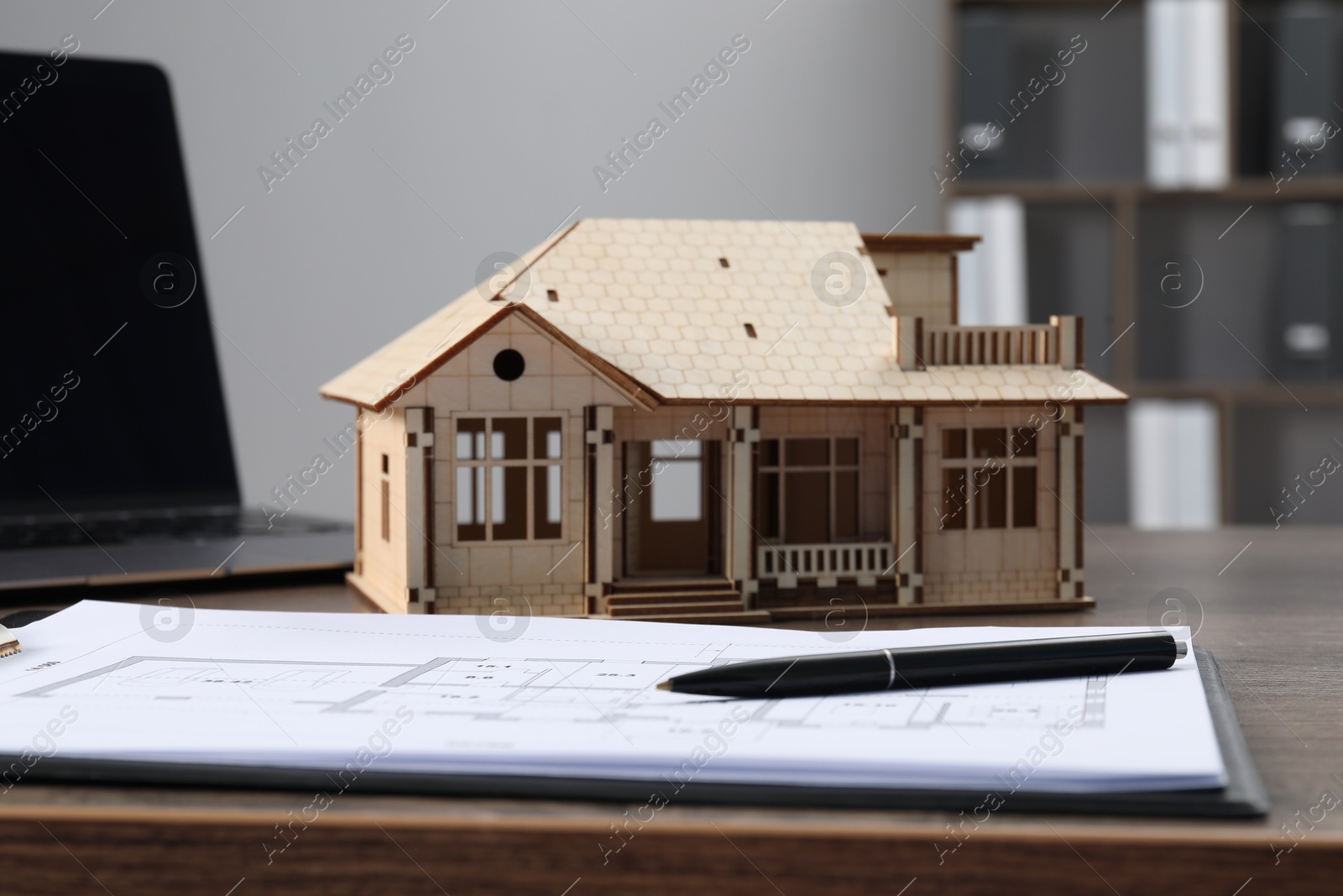 Real estate. House model, floor plan and laptop on wooden table indoors, closeup Photo of Real estate. House model, floor plan and laptop on wooden table indoors, closeup