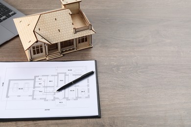 Photo of Real estate. House model, floor plan and laptop on wooden table. Space for text