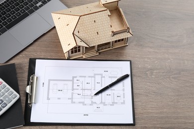 Photo of Real estate. House model, floor plan and laptop on wooden table