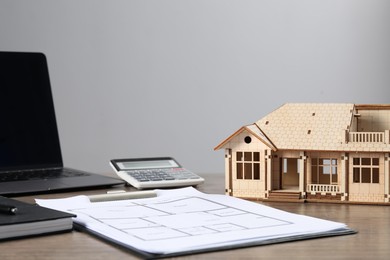 Photo of Real estate. House model, floor plan, laptop and calculator on wooden table. Space for text