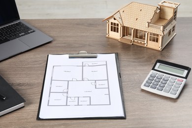 Photo of Real estate. House model, floor plan, laptop and calculator on wooden table