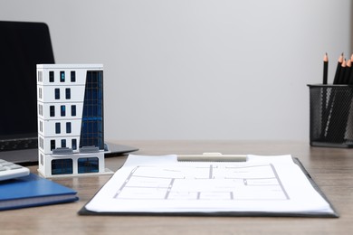 Photo of Real estate. Apartment building model, floor plan and laptop on wooden table. Space for text