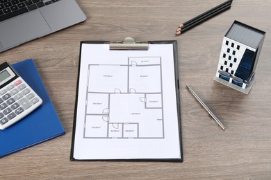 Photo of Real estate. Apartment building model, floor plan, calculator and laptop on wooden table