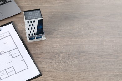 Photo of Real estate. Apartment building model, floor plan and laptop on wooden table. Space for text