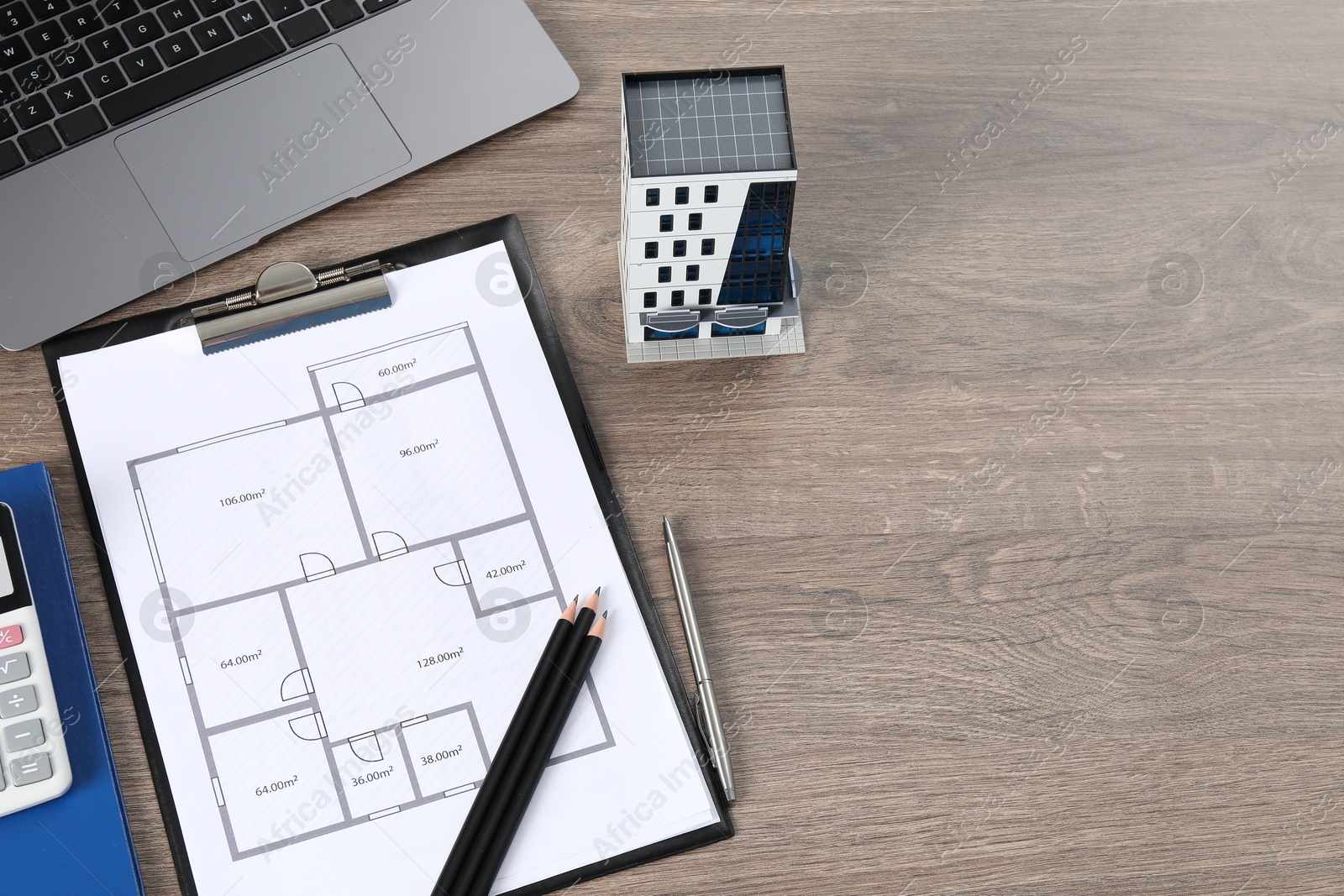 Real estate. Apartment building model, floor plan and laptop on wooden table, above view. Space for text Photo of Real estate. Apartment building model, floor plan and laptop on wooden table, above view. Space for text