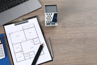 Photo of Real estate. Apartment building model, floor plan and laptop on wooden table, above view. Space for text