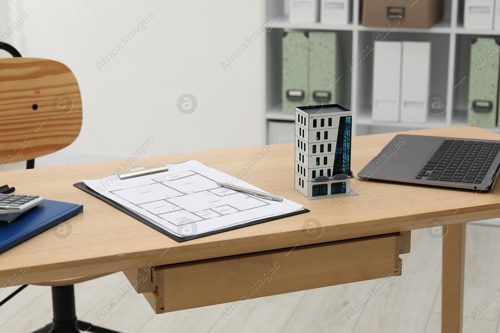 Real estate. Apartment building model, floor plan and laptop on wooden table indoors Photo of Real estate. Apartment building model, floor plan and laptop on wooden table indoors