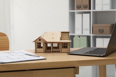 Photo of Real estate. House model, floor plan and laptop on wooden table indoors