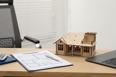 Photo of Real estate. House model, floor plan and laptop on wooden table indoors