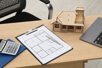 Photo of Real estate. House model, floor plan and laptop on wooden table indoors