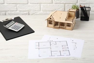 Photo of Real estate. House model, floor plan and calculator on white wooden table