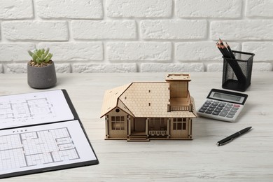 Photo of Real estate. House model, floor plan and calculator on white wooden table