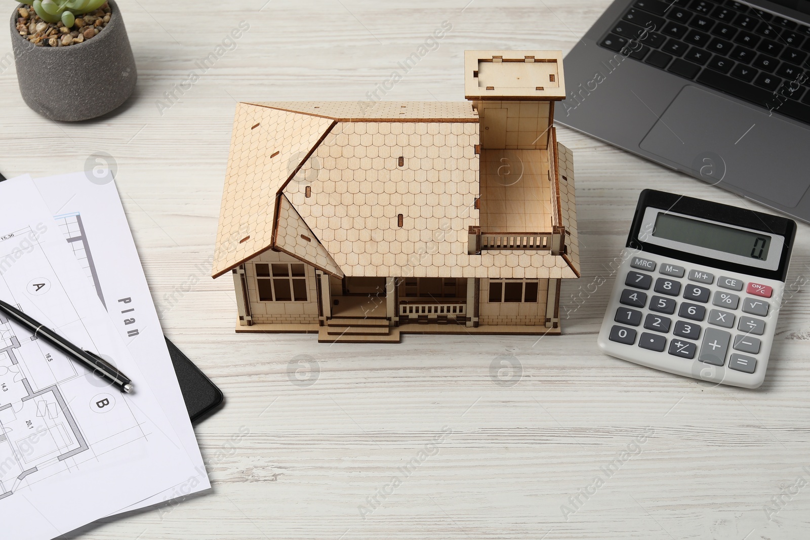 Photo of Real estate. House model, floor plan, calculator and laptop on white wooden table, closeup