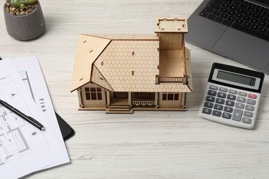 Photo of Real estate. House model, floor plan, calculator and laptop on white wooden table, closeup
