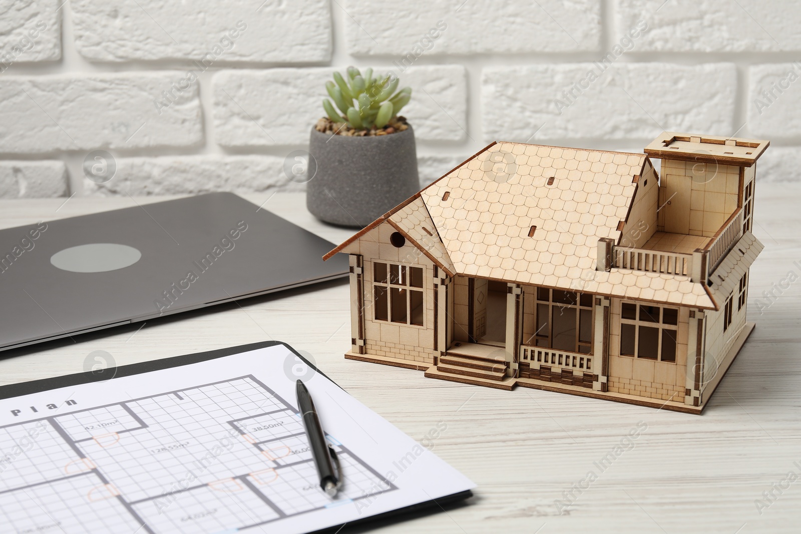 Real estate. House model, floor plan and laptop on white wooden table, closeup Photo of Real estate. House model, floor plan and laptop on white wooden table, closeup