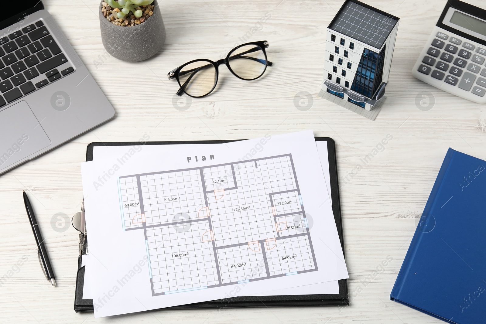 Photo of Real estate. Apartment building model, floor plan, calculator and laptop on white wooden table, above view
