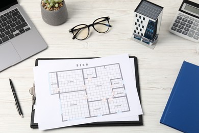 Photo of Real estate. Apartment building model, floor plan, calculator and laptop on white wooden table, above view