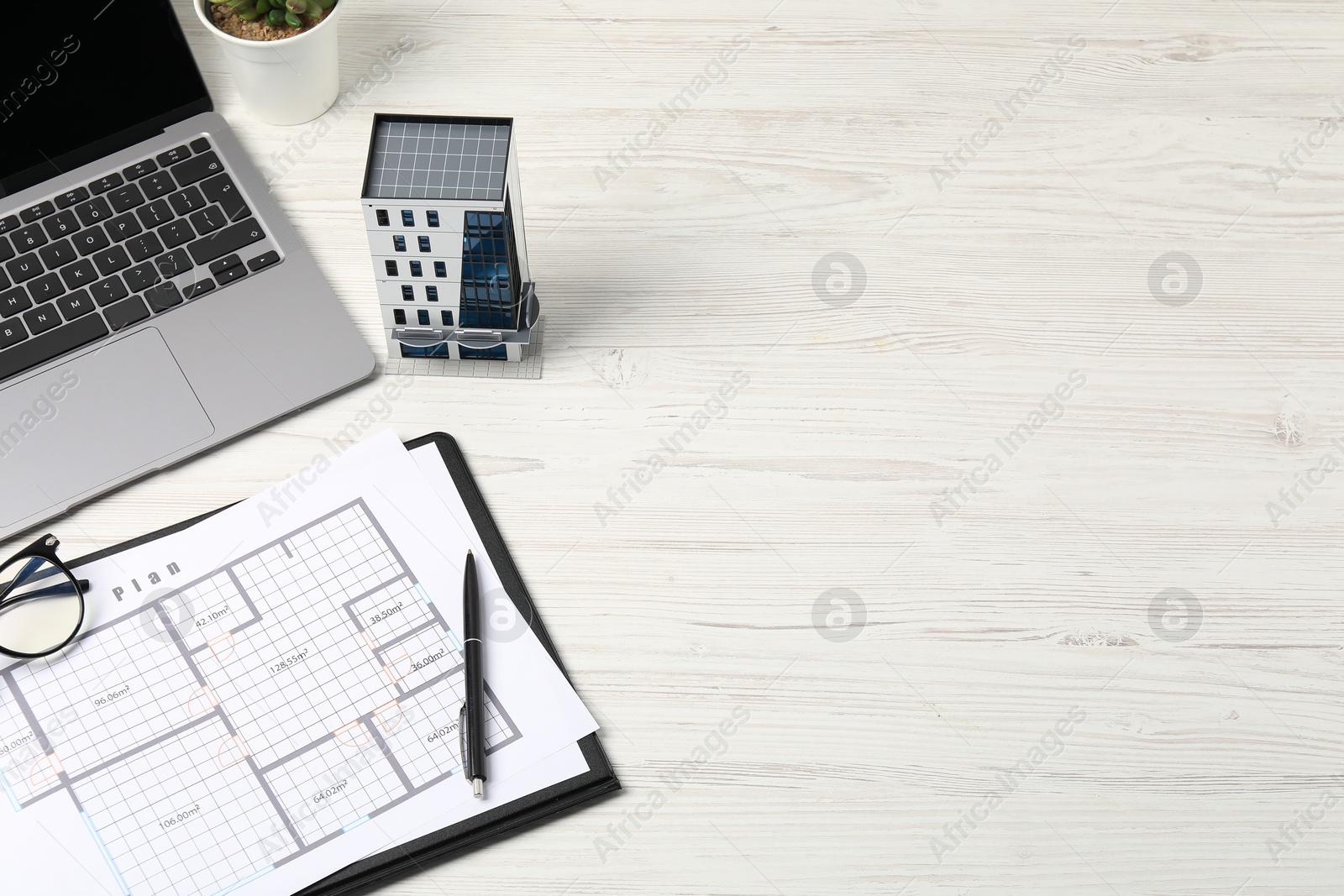 Real estate. Apartment building model, floor plan and laptop on white wooden table. Space for text Photo of Real estate. Apartment building model, floor plan and laptop on white wooden table. Space for text