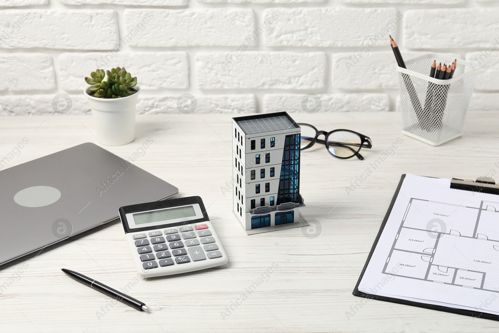 Real estate. Apartment building model, floor plan, calculator and laptop on white wooden table Photo of Real estate. Apartment building model, floor plan, calculator and laptop on white wooden table