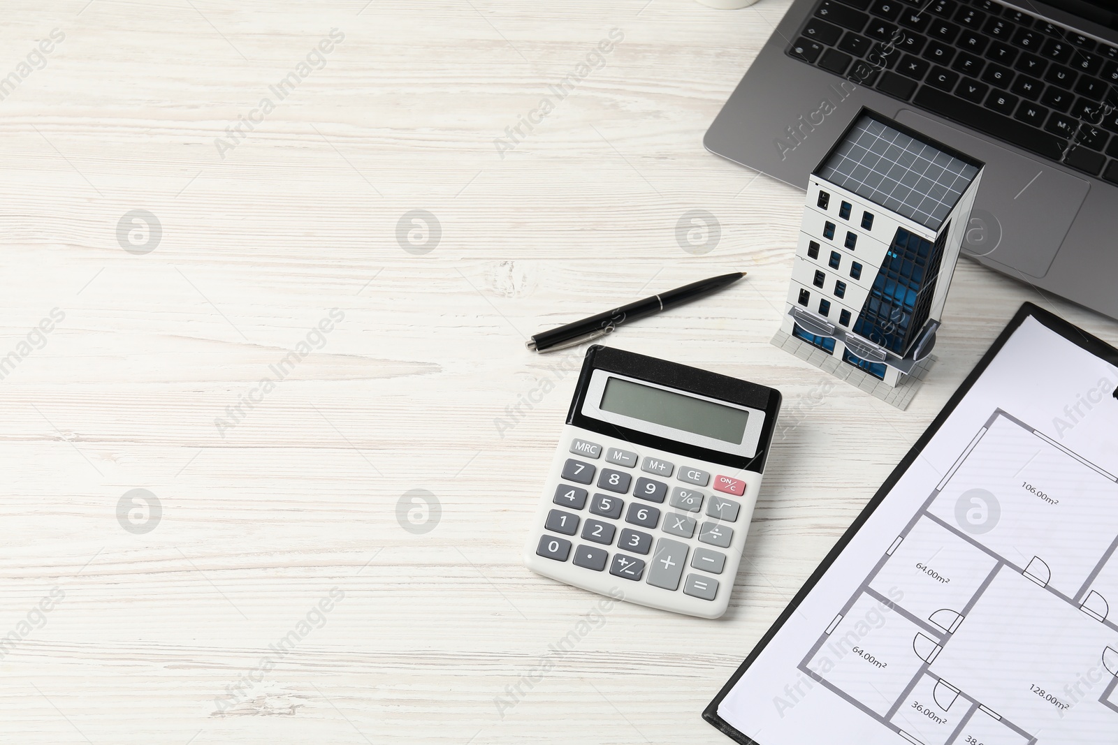 Real estate. Apartment building model, floor plan, calculator and laptop on white wooden table. Space for text Photo of Real estate. Apartment building model, floor plan, calculator and laptop on white wooden table. Space for text