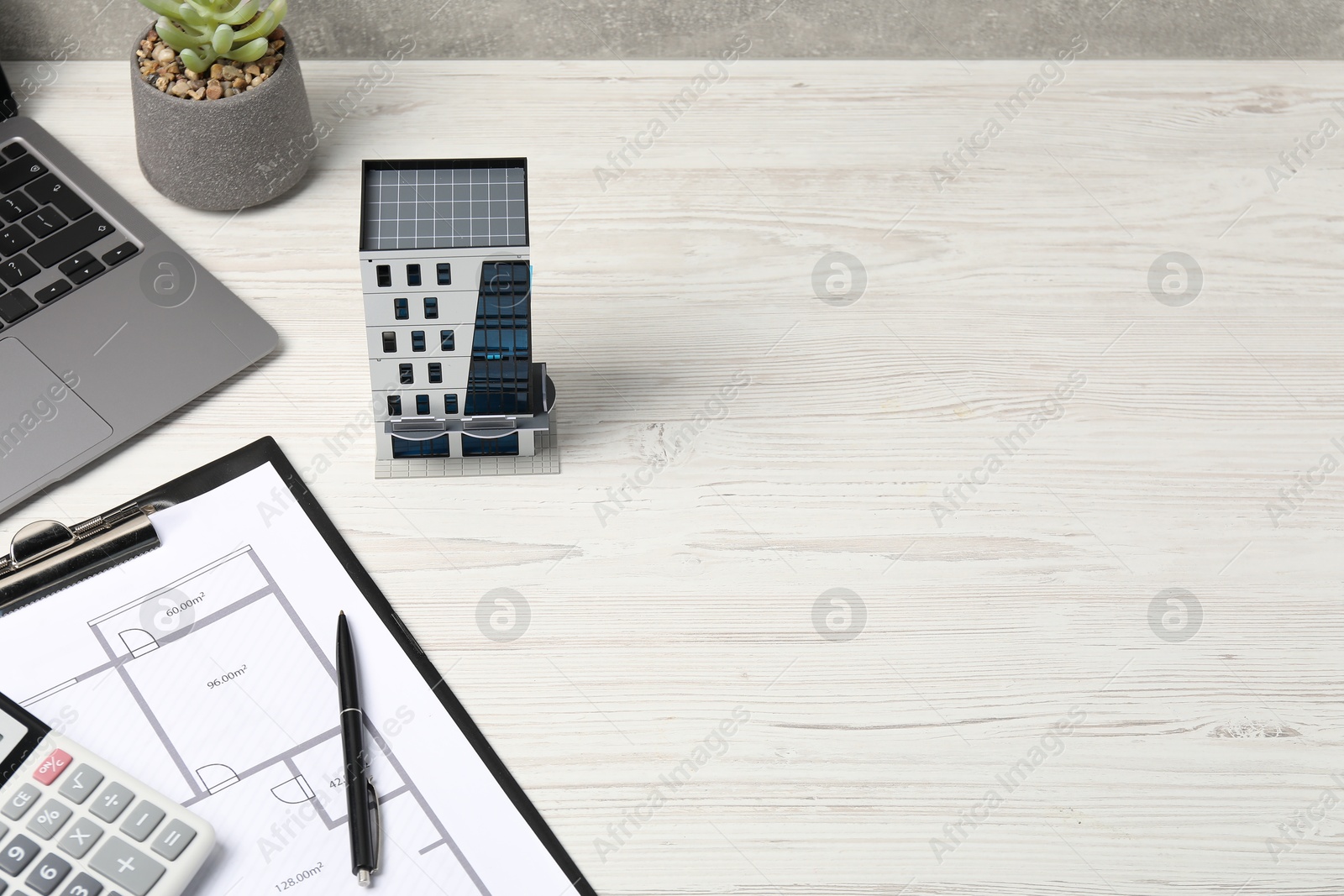 Real estate. Apartment building model, floor plan, calculator and laptop on white wooden table. Space for text Photo of Real estate. Apartment building model, floor plan, calculator and laptop on white wooden table. Space for text