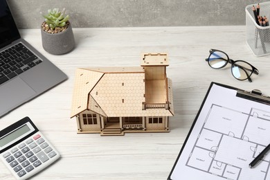 Photo of Real estate. House model, floor plan, calculator and laptop on white wooden table