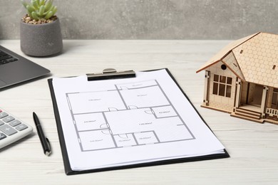 Photo of Real estate. House model, floor plan and laptop on white wooden table