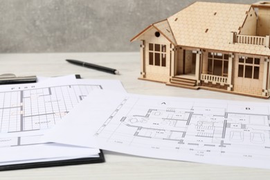 Photo of Real estate. House model and floor plan on white wooden table, closeup