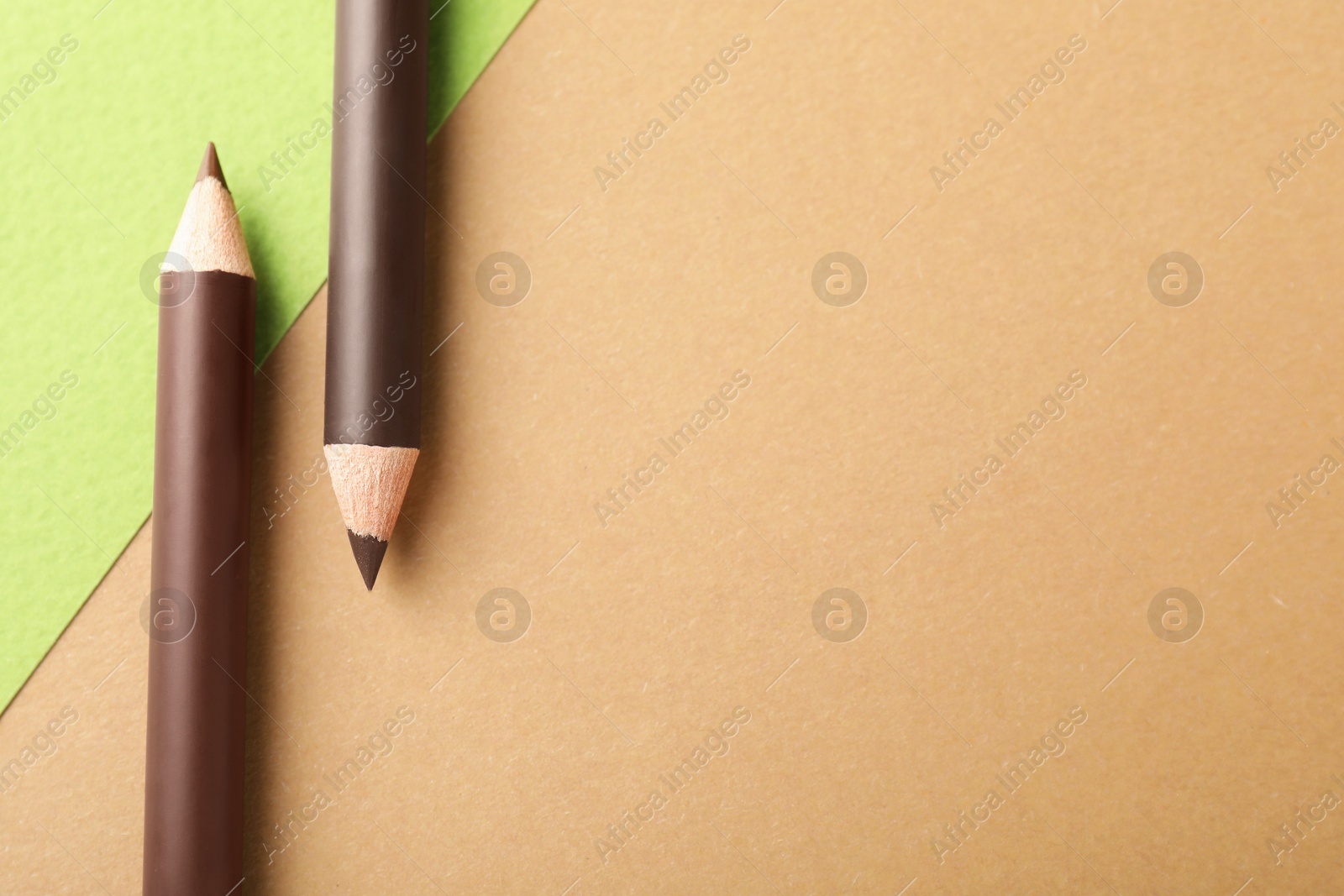 Brown eyebrow pencils on color background, flat lay. Space for text Photo of Brown eyebrow pencils on color background, flat lay. Space for text