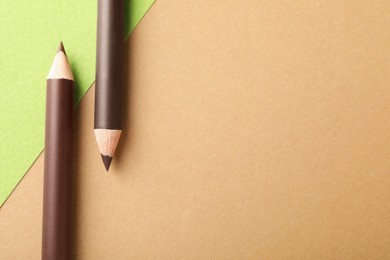 Photo of Brown eyebrow pencils on color background, flat lay. Space for text