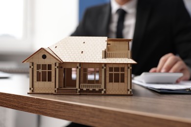 Photo of Real estate agent working at desk in office, focus on house model