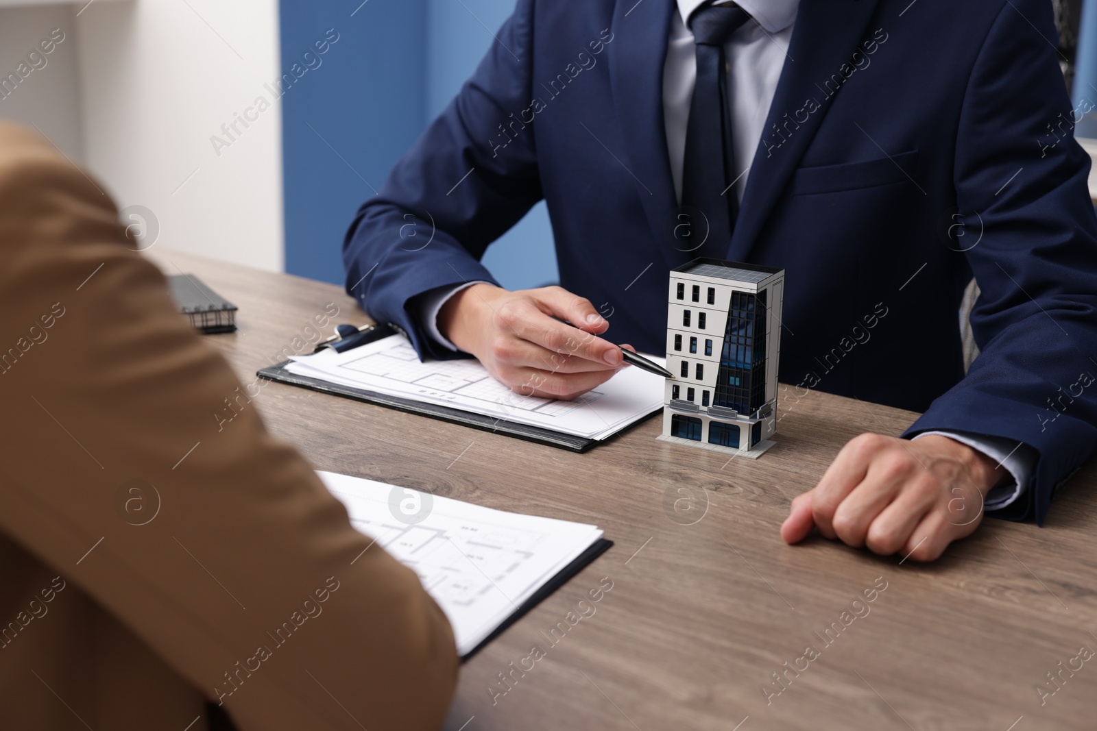 Real estate agent working with client at desk with house model in office, closeup Photo of Real estate agent working with client at desk with house model in office, closeup