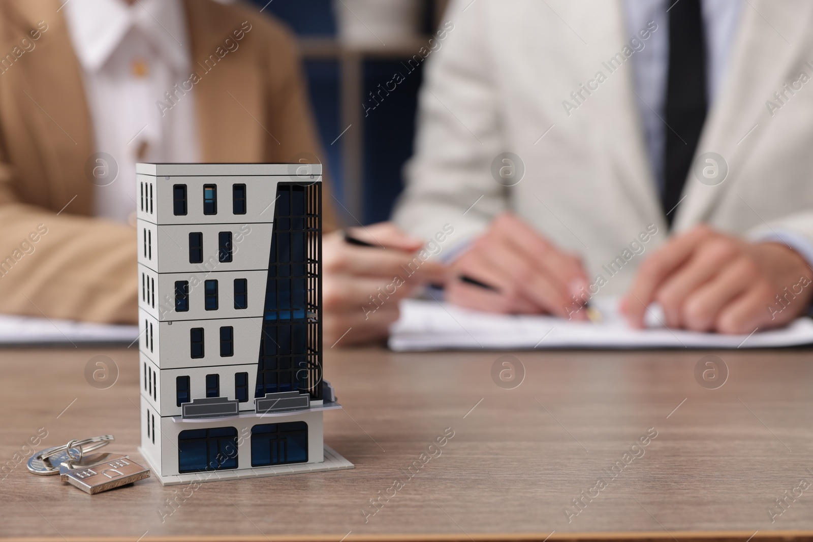 Real estate agent working with client at desk in office, focus on house model Photo of Real estate agent working with client at desk in office, focus on house model