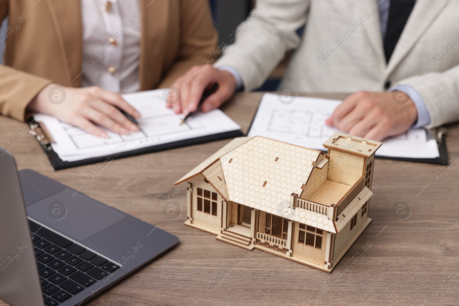 Real estate agent working with client at desk with house model in office, closeup Photo of Real estate agent working with client at desk with house model in office, closeup