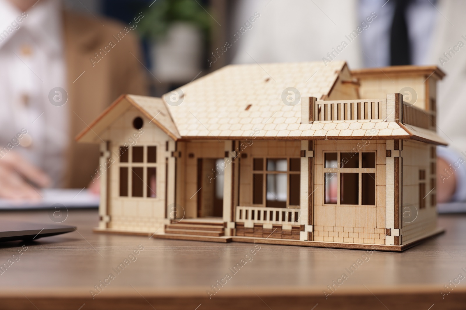 Real estate agent working with client at desk in office, focus on house model Photo of Real estate agent working with client at desk in office, focus on house model