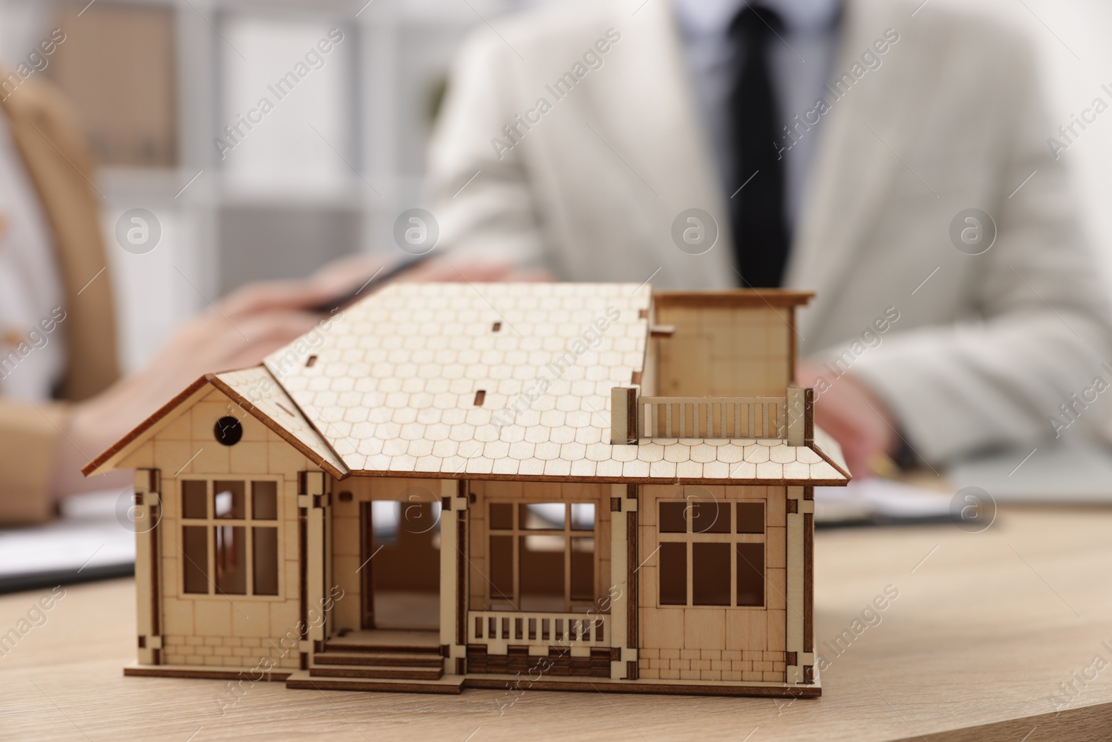 Real estate agent working with client at desk in office, focus on house model Photo of Real estate agent working with client at desk in office, focus on house model