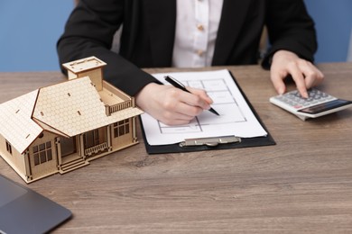 Photo of Real estate agent working at desk with house model in office, closeup
