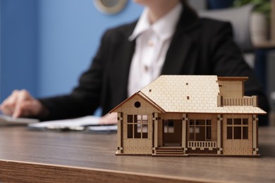 Photo of Real estate agent working at desk in office, focus on house model