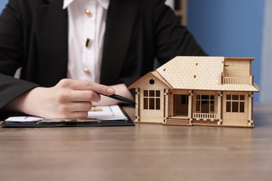 Photo of Real estate agent working at desk in office, focus on house model