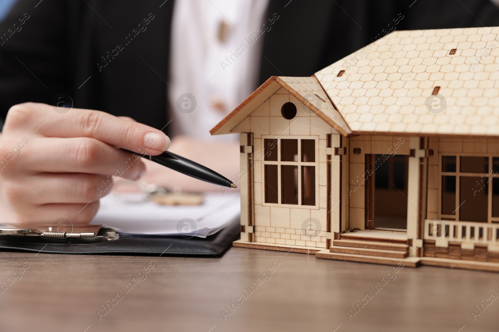 Real estate agent working at desk with house model in office, closeup Photo of Real estate agent working at desk with house model in office, closeup