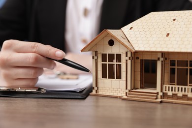 Photo of Real estate agent working at desk with house model in office, closeup