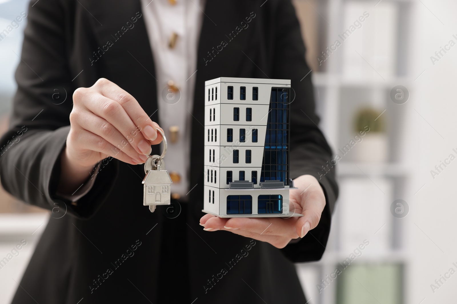 Real estate agent holding house model and key in office, closeup Photo of Real estate agent holding house model and key in office, closeup