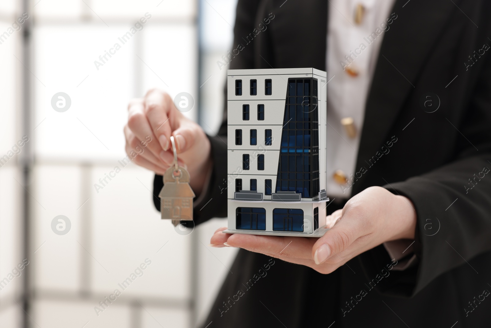 Real estate agent holding house model and key in office, closeup Photo of Real estate agent holding house model and key in office, closeup